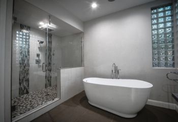 Detail of pebble tile shower flooring and mosaic columns in a luxury Westlake Village bathroom remodel by Drywall Repair & Remodeling.