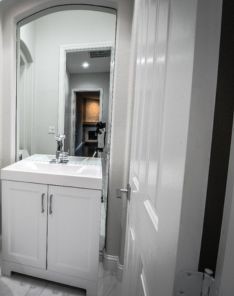 Contemporary bathroom vanity and toilet area in Westlake Village home, featuring sleek cabinetry and a large wall mirror.
