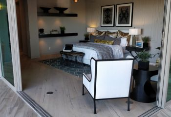 Spacious master bedroom in Simi Valley with wide sliding glass doors opening to a patio, modern wall paneling, and elegant lighting.