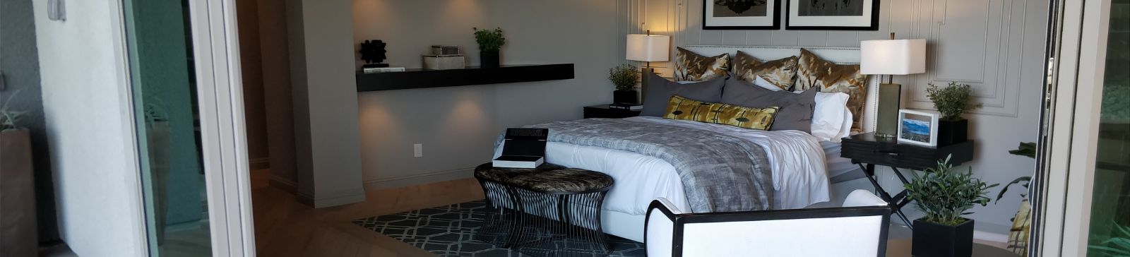 Spacious master bedroom in Simi Valley with wide sliding glass doors opening to a patio, modern wall paneling, and elegant lighting.